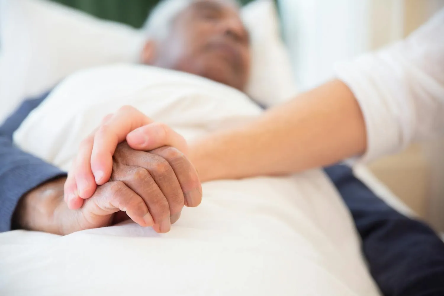 Eine Hand hält fürsorglich die Hand eines älteren Menschen
