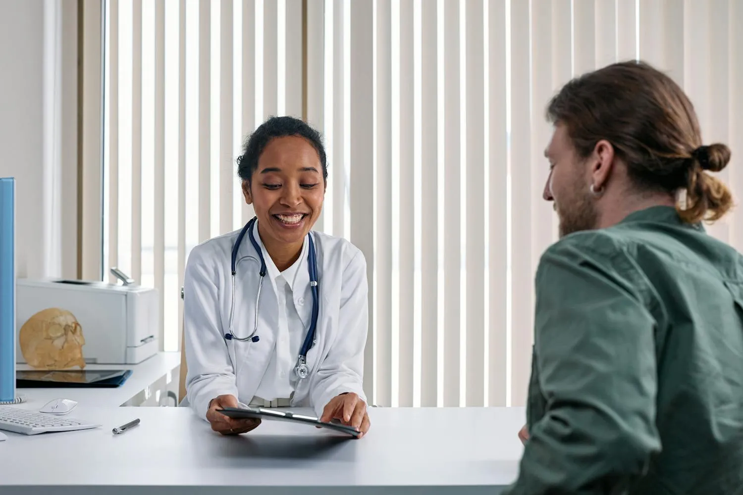 Ärztin im freundlichen Beratungsgespräch mit einer Patientin in hellen Praxisräumen